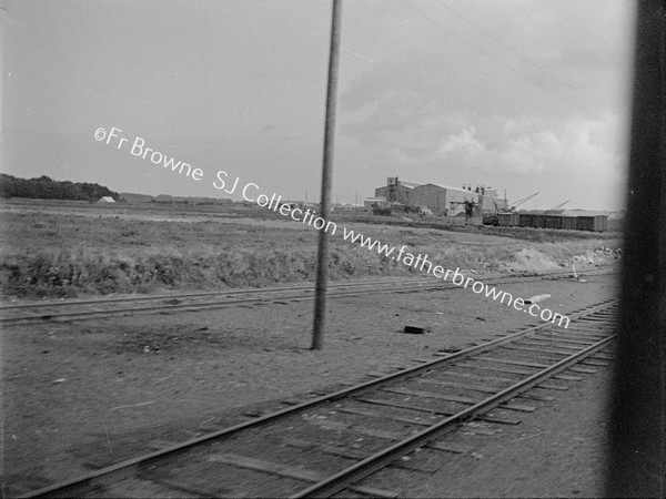 TRAIN TRACKS WITH FACTORY IN BACKGROUND